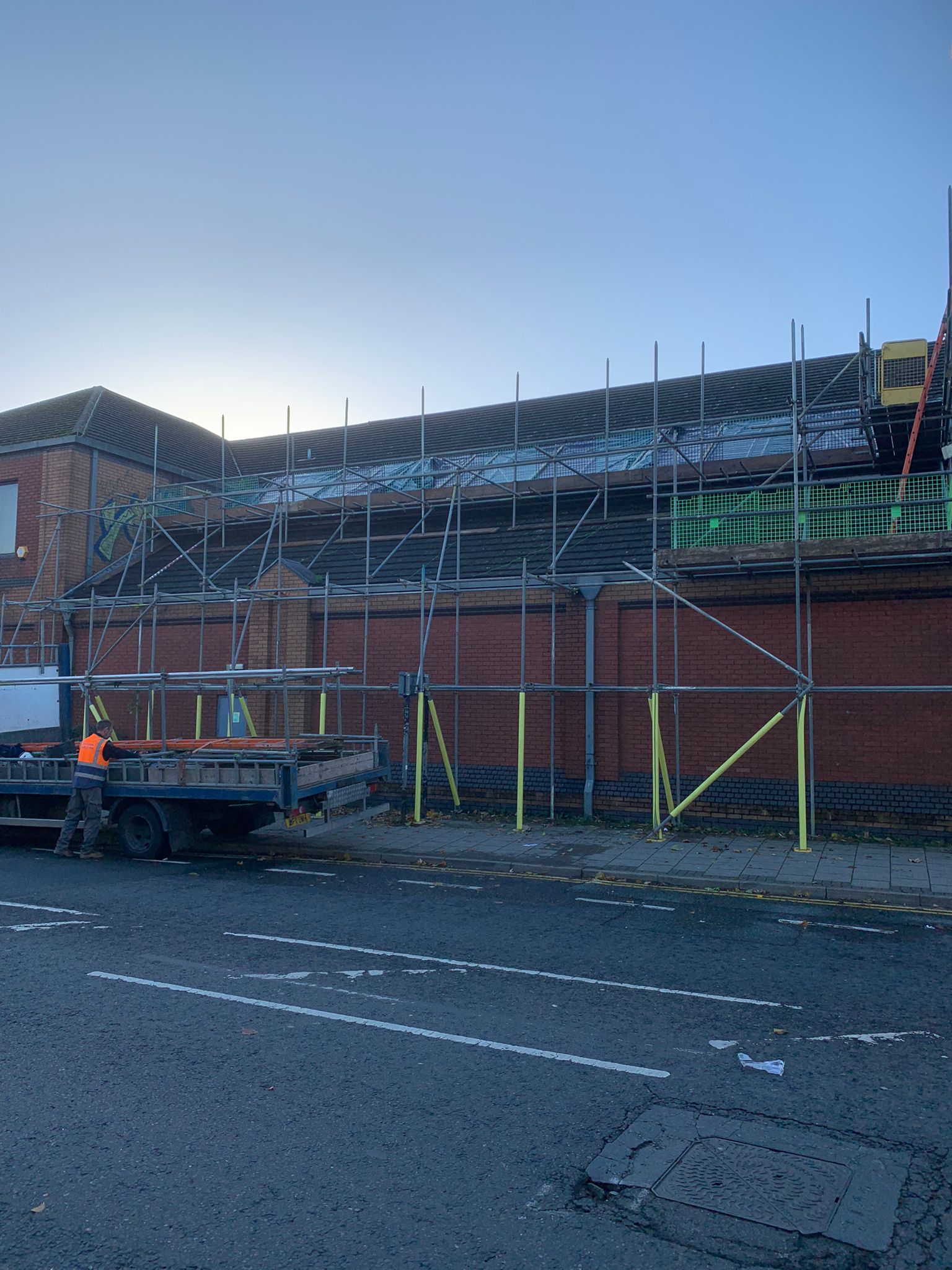 This is a photo of a commercial building with scaffolding ready for a replacement Roof. The roof installation is being done by Leicester Roofing Services